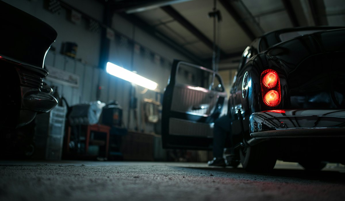 Officina in penombra con un'auto e una luce fredda